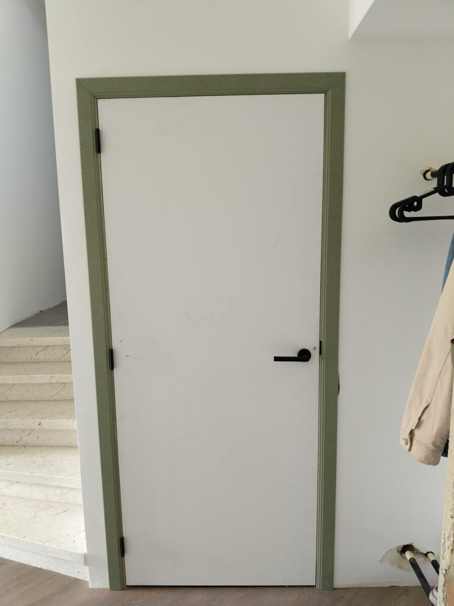 Witte binnendeur met groene omlijsting naast een trap Witte binnendeur met groene omlijsting naast een trap