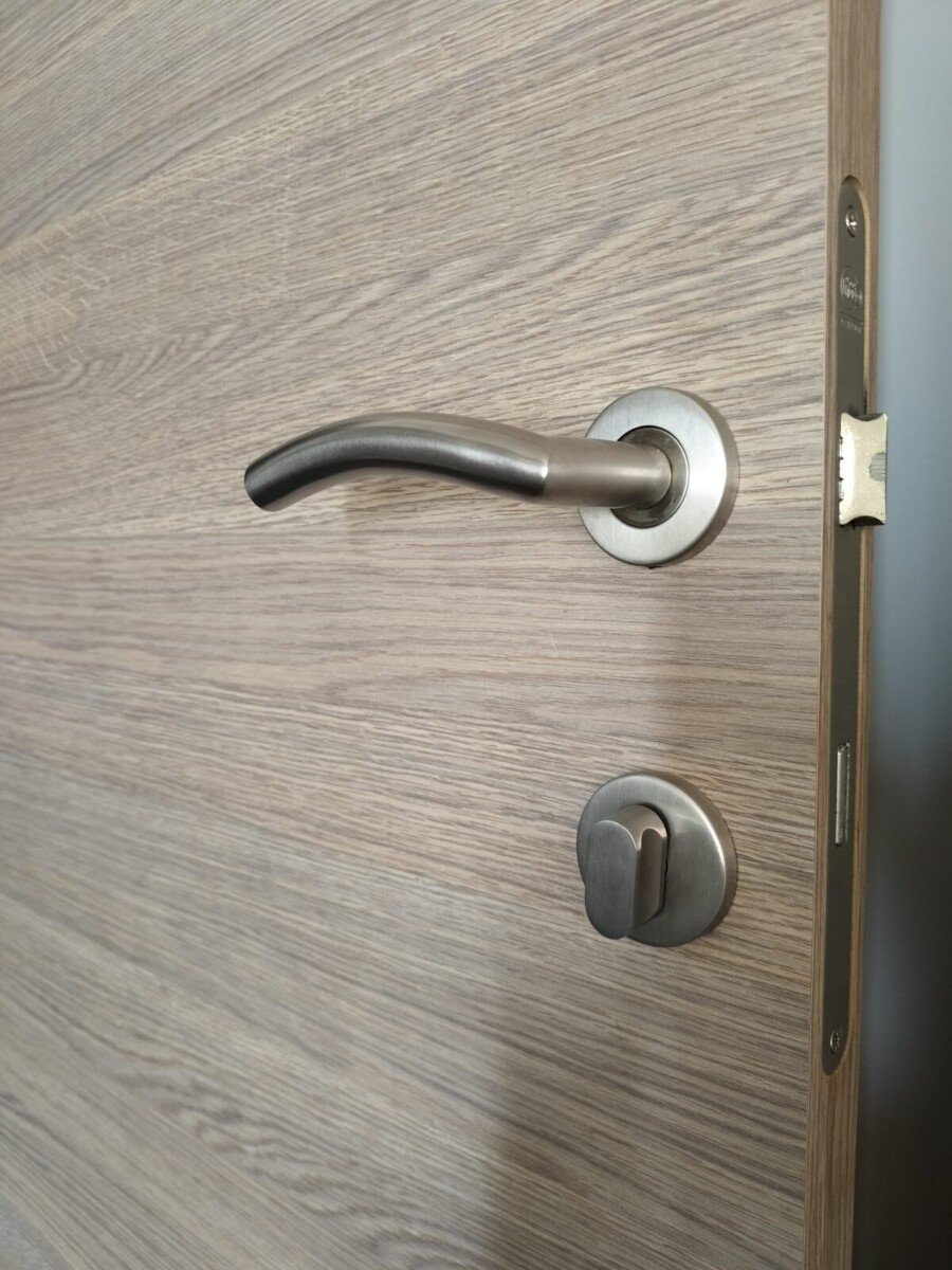 Detail van een deurklink en cilinderslot op een binnendeur in houtdecor Detail van een deurklink en cilinderslot op een binnendeur in houtdecor