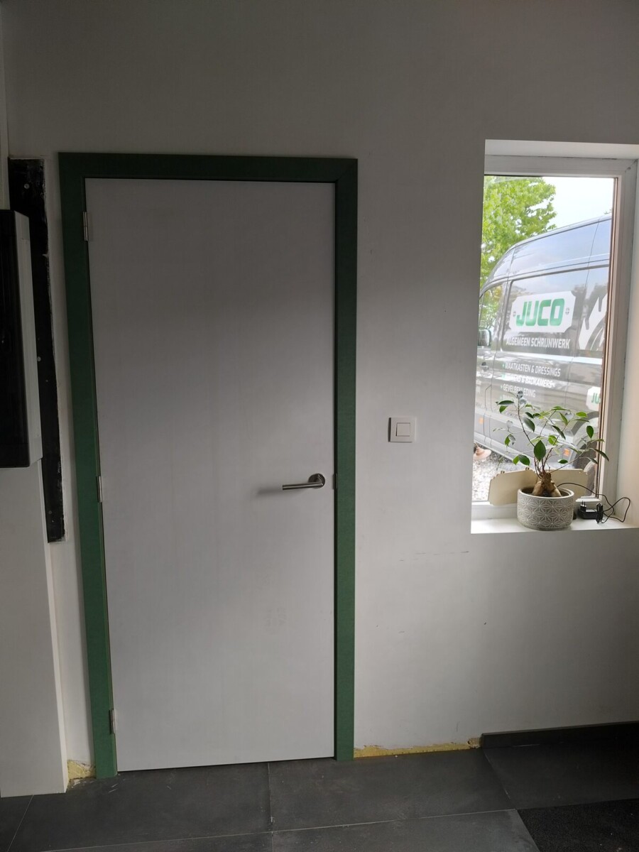 Witte binnendeur op maat met groene omlijsting naast een raam Witte binnendeur op maat met groene omlijsting naast een raam