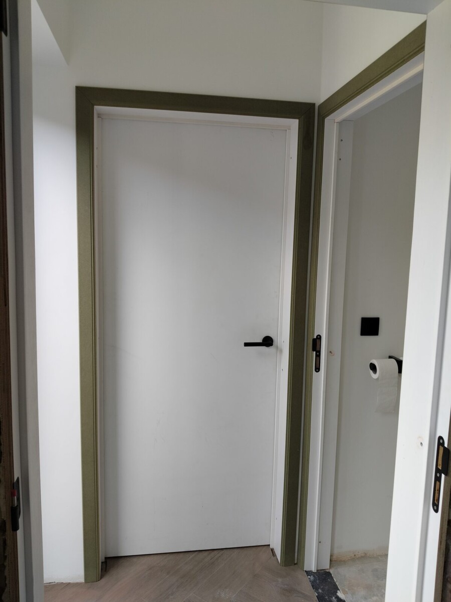 Twee witte binnendeuren met groene omlijsting in een gang Twee witte binnendeuren met groene omlijsting in een gang