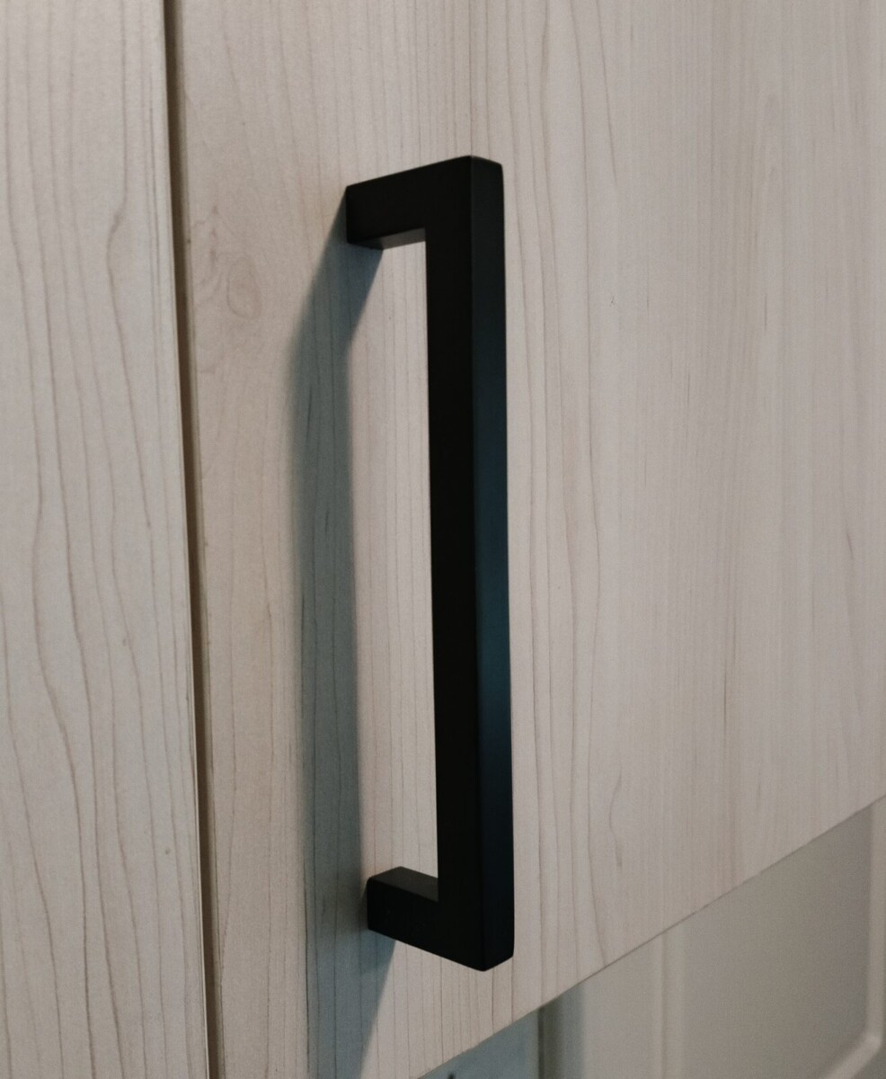 Detail van een zwarte greep op een licht keukenfront Detail van een zwarte greep op een licht keukenfront
